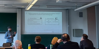 Zu sehen ist ein Seminarraum, in dem ein Vortag von Christoph Burzlaff gehalten wird. 