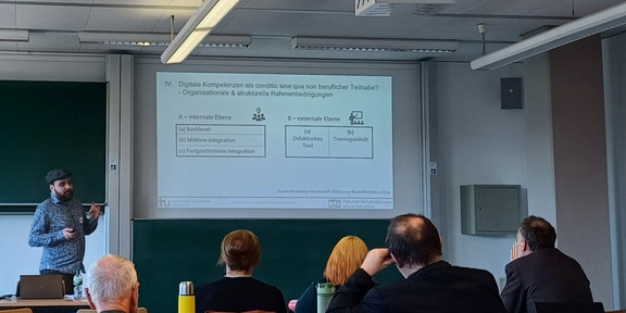 Zu sehen ist ein Seminarraum, in dem ein Vortag von Christoph Burzlaff gehalten wird.