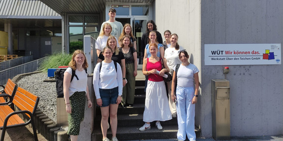 You can see twelve Students in front of the Über den Teichen workshop building.