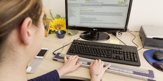 A blind student is learning at a computer using a special keyboard.